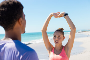 Obraz premium At beach, diverse couple stretching together, enjoying workout