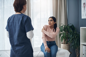 Obraz premium Woman, doctor and appointment with pain in arm, medical and patient conversation for health care concern. Clinic, muscle tension and talking with physiotherapy employee, injury and professional help