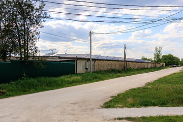 Rural area with a dirt road and a fence, solar panels on the roof