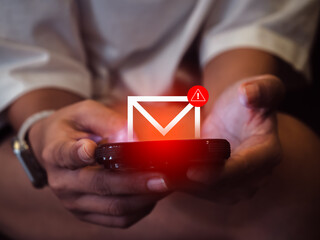 SMS spam and fake text message phishing from scammer concept. System hacked warning alert, email hack, scam malware spreading virus on message alert virtual on mobile phone screen in woman's hands.