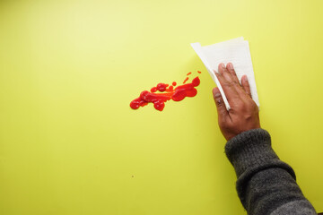 hand in blue rubber gloves cleaning tomato spill with a tissue 