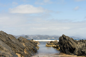 sailing on a yacht in the australian in the remote forest wilderness in spring, with waves breaking on a beach on the australian coastline