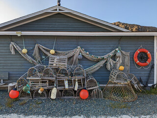 Fishing equipment, traps and nets are stacked against the blue wall of a Newfoundland home