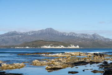 sailing on a yacht in the australian in the remote forest wilderness in spring, with waves breaking on a beach on the australian coastline