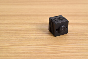 Closeup spy camera isolated on wooden background. Black security camera, Mini spy camera