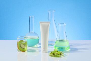 Blank label cosmetic tube placed on the white table with plenty glass utensils of experiment around, photo was taken from front view. Mock up for advertising, space for adding text