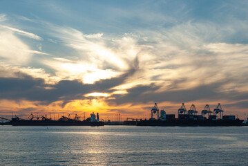 Obraz premium The sun sets over the industrial port area of Vancouver BC as viewed from a BC Ferry