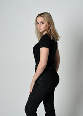 Close up portrait of beautiful blonde woman wearing modern black shirt and leather pants. Confident  standing pose with hand gestures, isolated on white studio background.