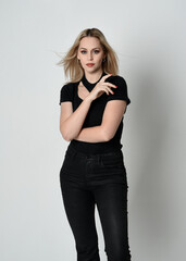 Fototapeta premium Close up portrait of beautiful blonde woman wearing modern black shirt and leather pants. Confident standing pose with hand gestures, isolated on white studio background.