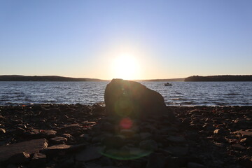 Sunset on the horizon behind a rock on the coast of Lake Wallenpaupack