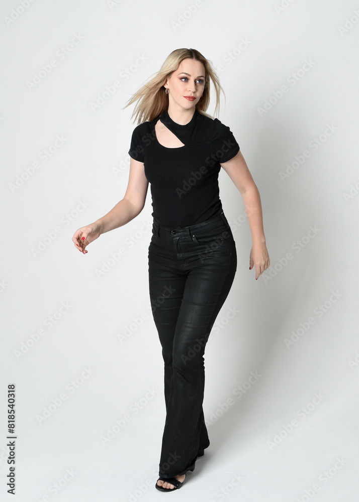 Poster Full length portrait of beautiful blonde woman wearing modern black shirt and leather pants. Confident standing pose with gestural hands presenting, silhouetted on white studio background.