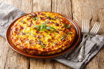 Crustless pie with bacon, egg, chicken, basil and cheese close-up on a plate on a wooden table. Horizontal