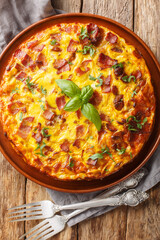 Crustless Quiche frittata with bacon, chicken and cheese closeup on the plate on the wooden table. Vertical top view from above