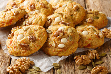 Autumn pumpkin cookies with white chocolate, nuts and seeds close-up on parchment on a wooden table. Horizontal - Powered by Adobe