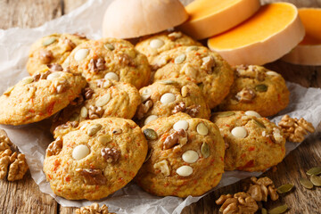 Pumpkin cookies on Halloween with white chocolate chips, walnut and pumpkin seeds closeup on the parchment on the wooden table. Horizontal