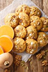 Pumpkin Walnut Chocolate Chip Cookies closeup on the parchment on the wooden table. Vertical top view from above