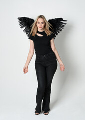 Full length portrait beautiful blonde girl wearing modern black shirt, leather pants, feather angel...