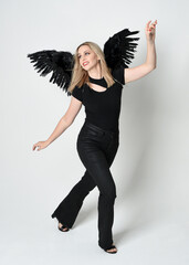 Full length portrait beautiful blonde girl wearing modern black shirt, leather pants, feather angel...