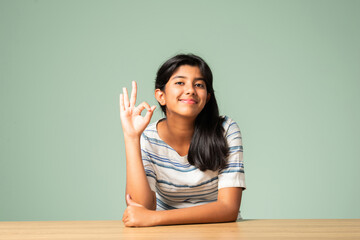 Indian asian small girl showing ok, perfect sign or thumbs up