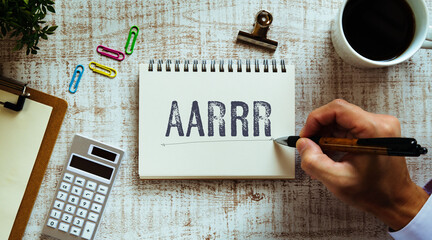 There is notebook with the word AARRR. It is an abbreviation for Acquisition, Activation, Retention, Referral, Revenue as eye-catching image.
