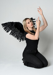 Full length portrait beautiful blonde girl wearing modern black shirt, leather pants, feather angel...