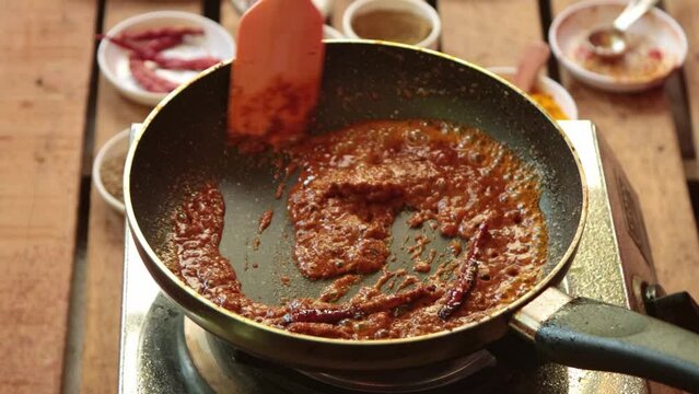preparing gravy by adding turmeric powder, salt, cumin powder,  red chili powder, tomato paste 