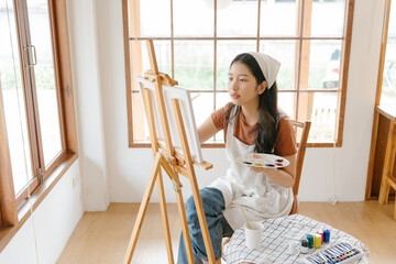 Asian young talented woman artist coloring on painting board in house. Attractive beautiful female...