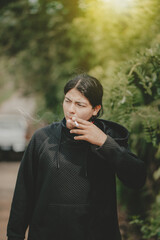 Young man smoking cigarette on the street. Portrait of handsome guy smoking outdoors