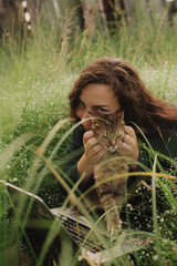 Woman using laptop in IT with cat outside in eco-farm. Online chat. Spend free time on nature. Concept working from home, slow life, staying connected, social distancing, internet. Part of the series