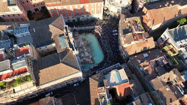 La fontana di Trevi a Roma, gremita di turisti, vista dall'alto.
Ripresa aerea con drone di Fontana di Trevi piena di visitatori in una giornata estiva.