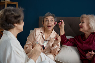 Funny old woman friends wearing pajamas doing makeup