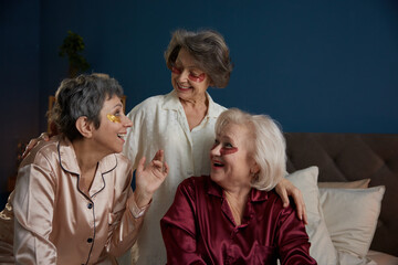 Laughing senior female friends speaking doing skincare rejuvenation procedure