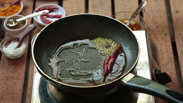 frying cumin seeds with red chili in mustard oil. 
