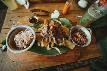 Traditional roast beef with slices of banana and gallopinto served on a wooden table.  Wooden table...