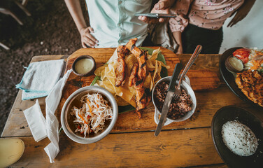 Person eating a traditional roast beef with slices of banana and gallopinto served on a wooden table.  Close up of traditional roast meats and gallopinto