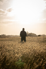 Man standing in yellow meadow in beautiful sunset light, facing forward 