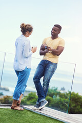 Couple, balcony and drinking for conversation in outdoor, bonding and together for love. People, terrace and speaking on holiday or vacation, alcohol and trees or ocean view for peace and talking
