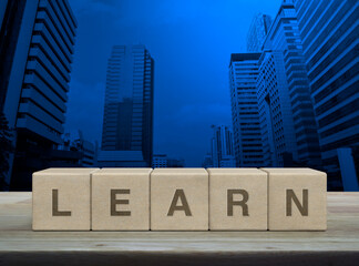 Learn letter on wood block cubes on wooden table over modern office city tower and skyscraper, Business, education and learning concept