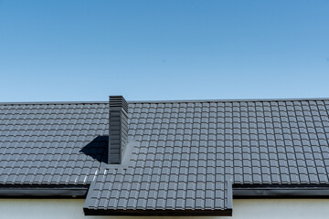 Composite material roof with chimney against blue urban sky