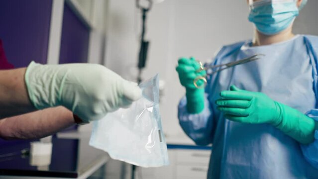in the operating room the lower surgeon in green gloves takes out scissors from a sterile package