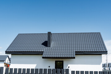 A charming cottage with a white facade, black composite material roof, and solar energy fixtures on...