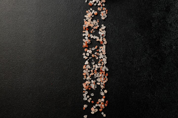 Colored Himalayan salt on a black background. Straight line Space for text