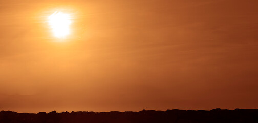 Sun rays at sunset and stones above Black sea coast in the evening, sunset in nature. coast line. Sunset above horizon line with sun setting down sun rays. mountains peak on bright sunset with cloud