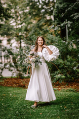 Riga, Latvia, - August 26, 2024 - Bride in white dress with large bouquet in park.