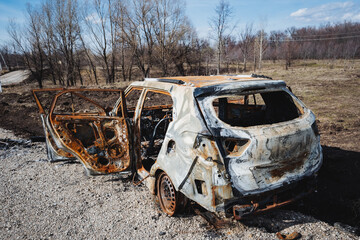 The car after the accident is in an open field outside the city, a burnt car, a rusty piece of...