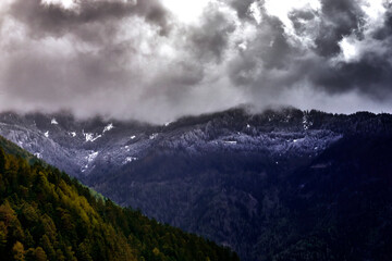 Alpine Peaks with Remnants of Snow and Visible Snow Line in Dark Clouds During Approaching...