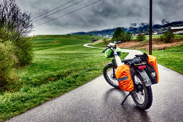 Obraz premium Heavily Loaded E-Fatbike on a Bike Path in an Austrian Alpine Valley During Rainy Weather
