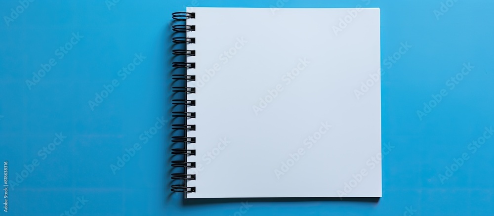 Poster A black notebook placed by itself against a blue backdrop leaving ample space for additional images or text