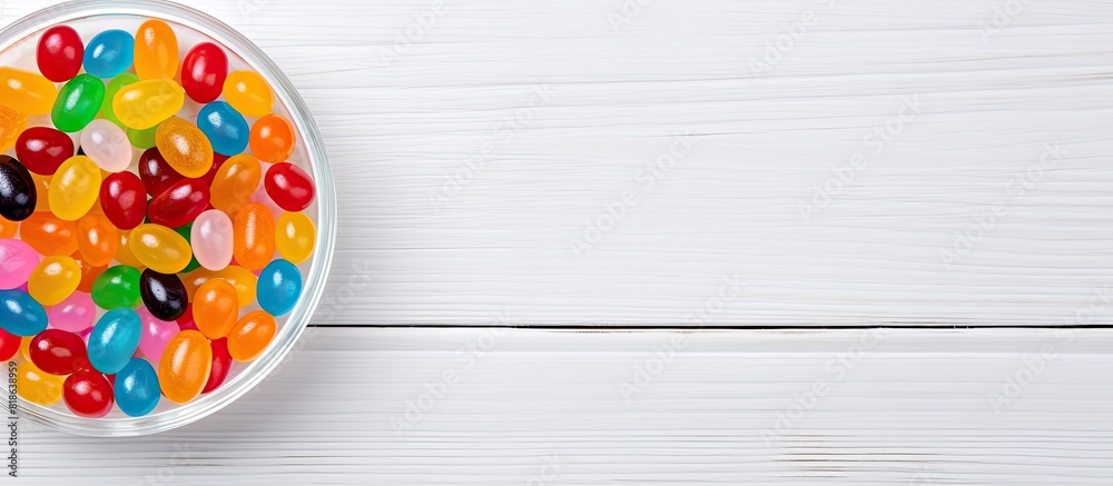 Poster top view of a bowl filled with vibrant jelly beans placed on a white wooden surface ample copy space