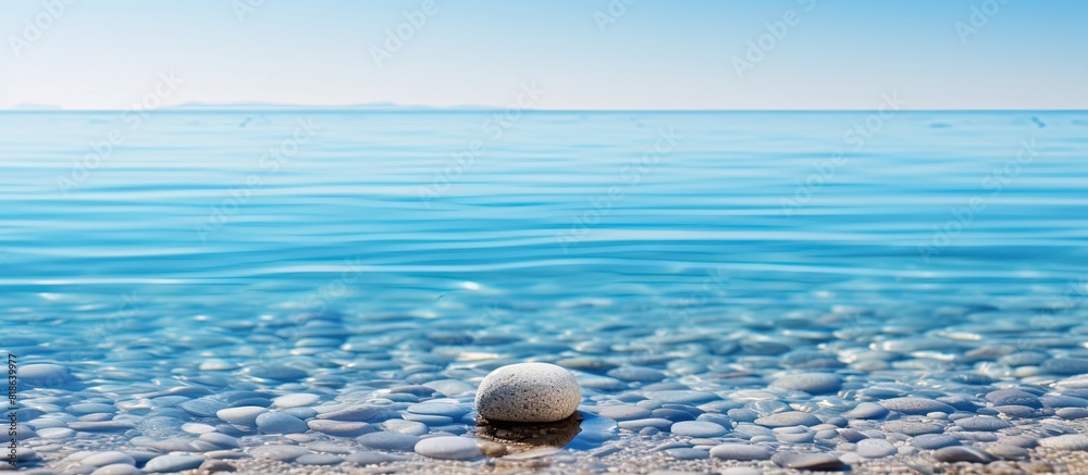 Poster A pebble resting in the clear water on the sandy beach creating a serene and natural background for any desired content Copy space image